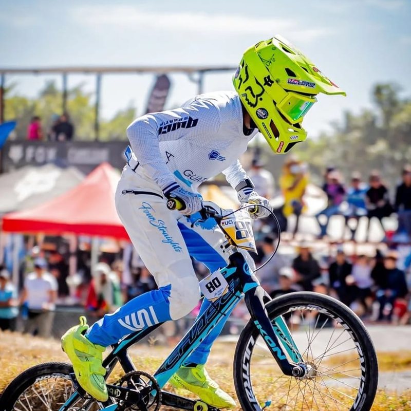 Piloto de BMX con casco amarillo saltando durante una competencia